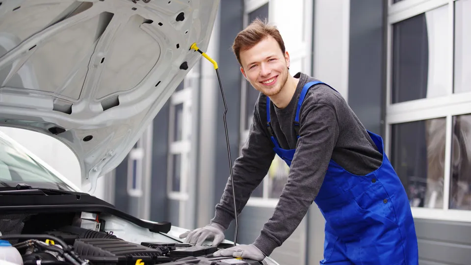 Kfz-Mechatroniker arbeitet im Motorraum eines Autos